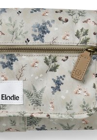 Kukkarokangas, jossa on kukkakuosi vaaleassa beessissä, esittelee kaneja ja lehtiä. Kultainen vetoketju nahkavetimellä ja brodeerattu brändilogo.