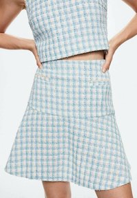 Conjunto de top corto y falda de tela a cuadros en azul claro y blanco, con un tejido texturizado y dos bolsillos delanteros en la falda.