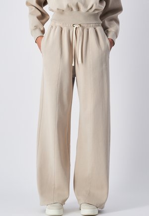Beige wijde sweatpants gemaakt van een zachte katoenmix, met een elastische tailleband met trekkoord, zijzakken en gestikte details.