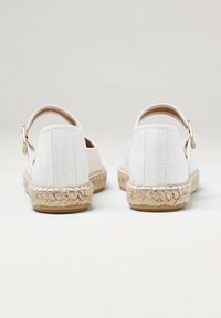 Baskets espadrilles blanches avec une tige en toile texturée, une sangle à la cheville et des détails en jute tressé le long de la semelle.