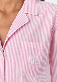 Haut de pyjama rayé rose et blanc avec un col en V, une poche plaquée ornée de "RL" brodé, et une texture douce et lisse.