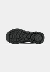 Black athletic shoe sole with textured rubber traction patterns, featuring grooves and rounded edges for enhanced grip and flexibility.