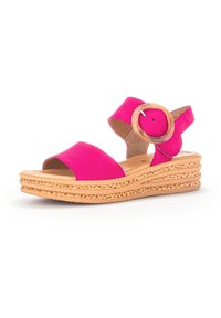 Sandali wedges in suede fucsia con punta aperta, cinturini larghi e un'applique circolare in legno attorno alla caviglia. Suola in sughero chiaro e testurizzato.