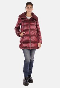 Cappotto imbottito bordeaux con grande colletto, zip frontale e tasche laterali; presenta una texture lucida e liscia e un design trapuntato.