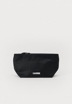 Saco de nylon preto com fundo plano e arredondado, fecho de zíper e um detalhe de logótipo em metal. Textura suave sem padrões visíveis.