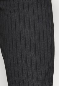Black striped fabric with vertical lines; textured surface; close-up view emphasizing the pattern and material without additional details.
