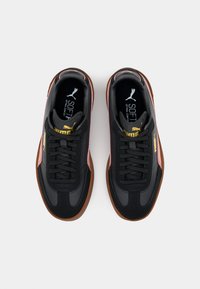 Melni sporta apavi ar gludu sintētisku virsu, rozā akcentiem, apaļu pirkstu daļu un gumijas zoli; ar auklām un "SOFT" zīmolu uz iekšējās zoles.