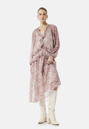 Woman wearing a pink paisley-patterned midi dress with ruffles and long sleeves, paired with knee-high white heeled boots.