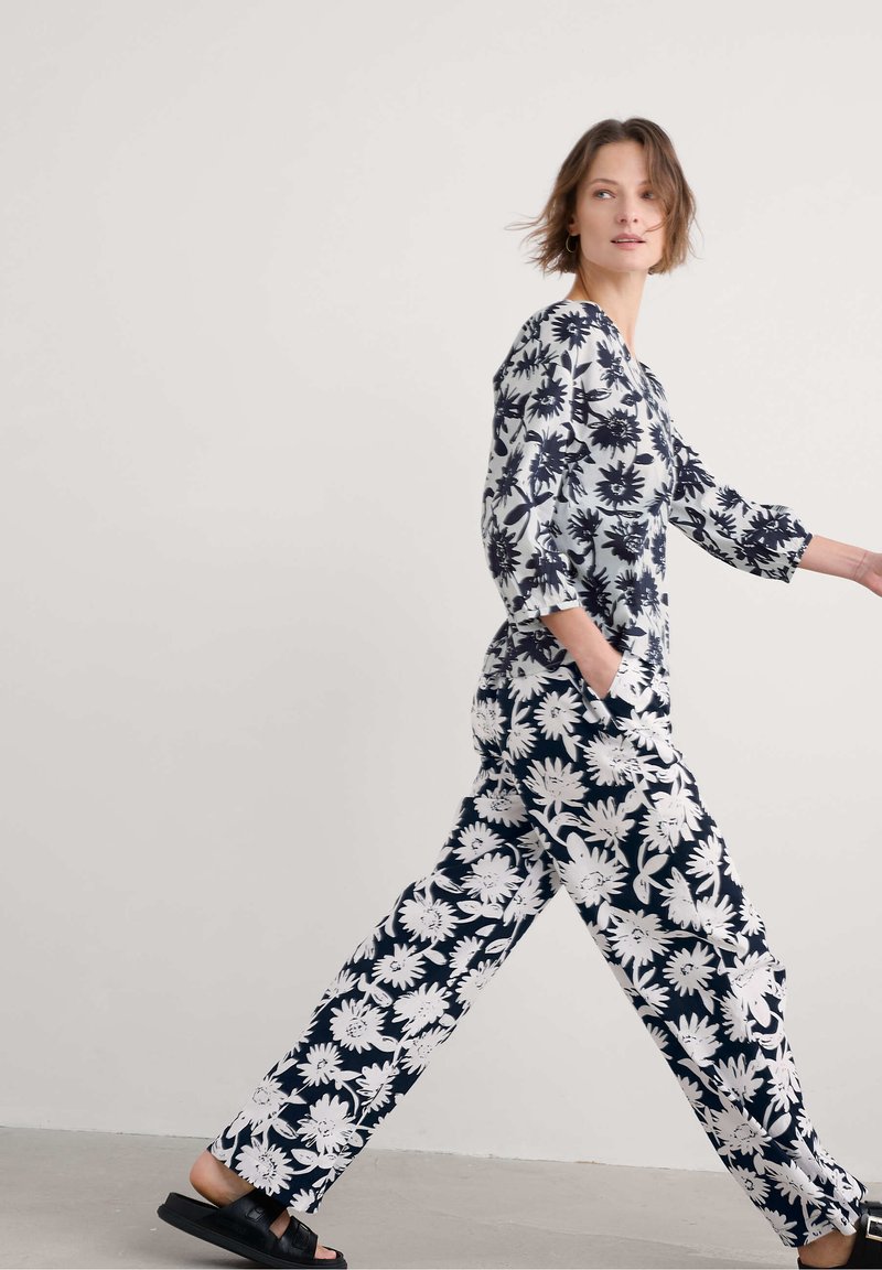 Blumiger Overall in Marineblau und Weiß, mit langen Ärmeln, weitem Bein und Seitentaschen, aus glattem Baumwollstoff und mit kräftigem Blumenmuster.