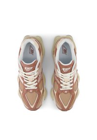Zapatillas marrones y beige con materiales de malla y ante, suela gruesa color crema, cordones blancos y detalles del logo en la lengüeta.
