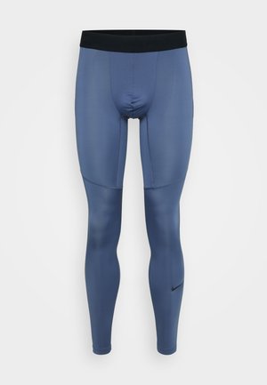 Nike Pro compressiekleding leggings in een middenblauwe kleur, met een zwarte elastische tailleband en een gladde, rekbare stof met naadaccenten.