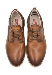 Zapatos de cuero marrón con punta redondeada y cierre de cordones. Cuenta con un cuello y una plantilla acolchada, con un logo rojo y acentos de costura blanca.