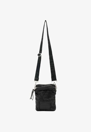 Black quilted crossbody bag with adjustable strap, silver hardware, zip closure, and textured branding on strap. Compact and angular design.