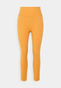 Leggings mostaza de tiro alto, sin costuras, con un patrón texturizado y un pequeño logo blanco en el muslo superior.