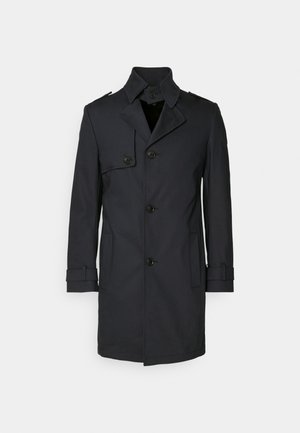 Trench coat blu navy realizzato in un tessuto liscio e resistente, con un davanti doppiopetto, bottoni grandi e polsini delle maniche regolabili.