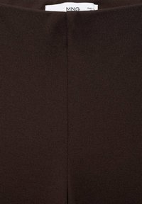 Pantalons en tissu extensible marron avec une texture lisse, présentant une couture centrale à l'arrière et une étiquette attachée à la taille.
