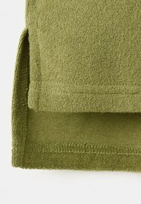 Olive green terry cloth fabric with a side slit and layered hem showing knit texture and stitching details.
