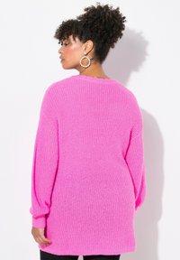 Maglione oversize rosa a maglia con texture a coste, scollatura rotonda e maniche lunghe. Presenta una vestibilità ampia e un design semplice.