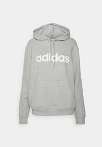 Felpa grigia realizzata in misto cotone. Presenta un grande logo bianco "adidas" sulla parte anteriore, cappuccio con lacci e una tasca a marsupio.