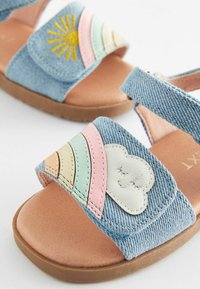 Jeanssandaler med en brun innersula. Har färgglada, lager-på-lager remmar med ett sol- och moln-design. Justerbara remmar för bra passform.