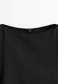 Vêtement noir avec un large col rond. Confectionné dans un tissu lisse et texturé. L'étiquette intérieure indique les informations de taille.