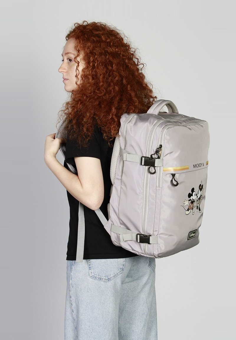 Sac à dos gris en matériau nylon lisse, orné d'un imprimé Mickey Mouse, avec des bretelles ajustables, des éléments réfléchissants et un compartiment principal zippé.