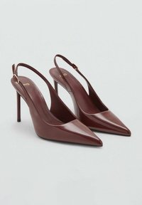 Pár lesklých vínových lodiček se špičatou špičkou a tenkými stiletto podpatky s pásky se zlatými sponami na světlém pozadí.