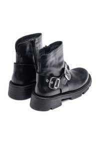 Black leather ankle boots featuring a side zipper, thick black sole, and wide metal buckle strap around the mid-section.