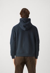 Felpa blu navy con un grande cappuccio regolabile, polsini e orlo a costine; materiale morbido in cotone misto; vista posteriore che mostra la semplicità del design.