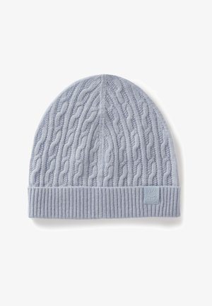 Světlá modrá pletená čepice s copánkovým vzorem a žebrovaným lemem. Na boku je malá měkká látková nášivka s logem.