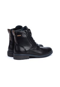 Bottines en cuir noir avec fermeture éclair sur le côté, œillets en métal et accents de talon marron. Détails cousus et semelle en caoutchouc avec bord bleu.