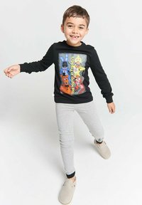Black long-sleeve shirt featuring a colorful graphic of cartoon characters from "Five Nights at Freddy's." Paired with gray leggings and light slippers.