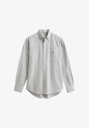 Raidallinen nappipaita pitkillä hihoilla, valmistettu puuvillasta. Vasemman rinnan kohdalla tasku, ja paidassa on kaartuva helma. Värit: valkoinen ja tummansinivalkoiset raidat.