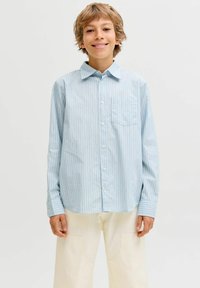Světle modrá pruhovaná košile na knoflíky s límečkem, obsahující náprsní kapsu a dlouhé rukávy, nošena s světle barevnými širokými kalhotami.