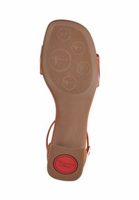 Soletta in sintetico color tan con motivi di presa testurizzati, punta arrotondata e logo rosso "Tamaris Comfort"; cinturino alla caviglia regolabile visibile.