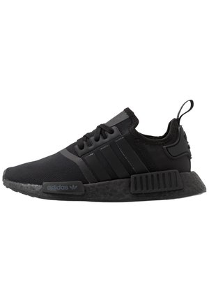 Basket Adidas NMD noire avec tige en mesh, semelle en caoutchouc noir, trois bandes sur le côté et languette au talon.