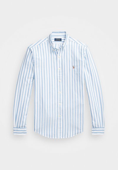 Camisa de botões azul e branca com riscas, mangas longas, colarinho e um pequeno logótipo bordado no lado esquerdo do peito. Tecido de algodão.