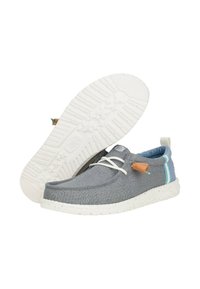 Zapatillas de lona grises con suela de goma blanca, diseño de cordones y acentos de cuero. Presentan una raya azul y blanca en el talón.