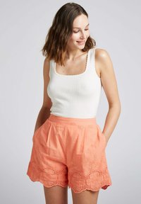 Débardeur blanc à côtes avec un col carré associé �à un short rose corail orné de broderies florales et d'une finition en dentelle festonnée.