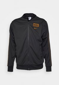 Svart Nike zip-up jacka med orange logotyp och ränder på ärmarna, ribbade muddar och hög krage.