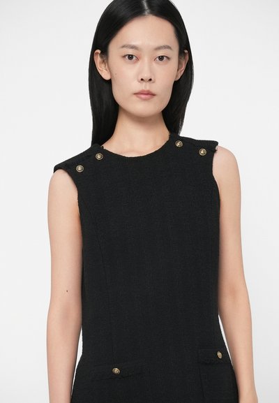 Fekete ujjatlan ruha textúrált anyagból, arany gombos díszítéssel a vállakon és két elülső zsebbel. Egyszerű, szabott dizájn.