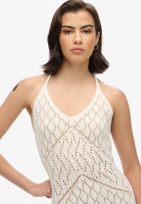 Strikket halterneck-top i off-white med diamant- og zigzag-mønstre, i en struktureret finish og justerbare stropper.