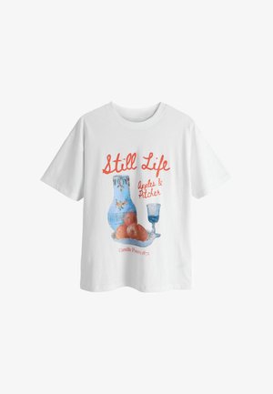 Biały bawełniany t-shirt z nadrukiem martwej natury przedstawiającym jabłka, niebieski dzbanek i szklankę, z czerwonym napisem "Martwa natura" oraz nazwiskiem artysty.