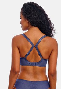 Námořnická modrá podprsenka s nastavovacími ramínky a texturovaným prošíváním. Obsahuje design s křížovými zády a zapínání na háček a oko pro bezpečné uchycení.
