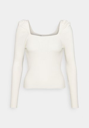 Haut en maille côtelée blanc cassé à manches longues avec encolure carrée et épaules bouffantes froncées, silhouette ajustée.