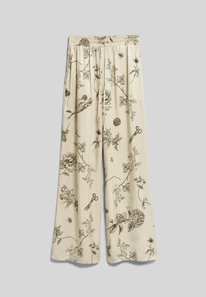 Pantalon beige à jambes larges avec des croquis noirs de botanique et d'insectes, comprenant des fleurs, des feuilles, des abeilles et des ciseaux, doté d'une taille élastique avec cordon.