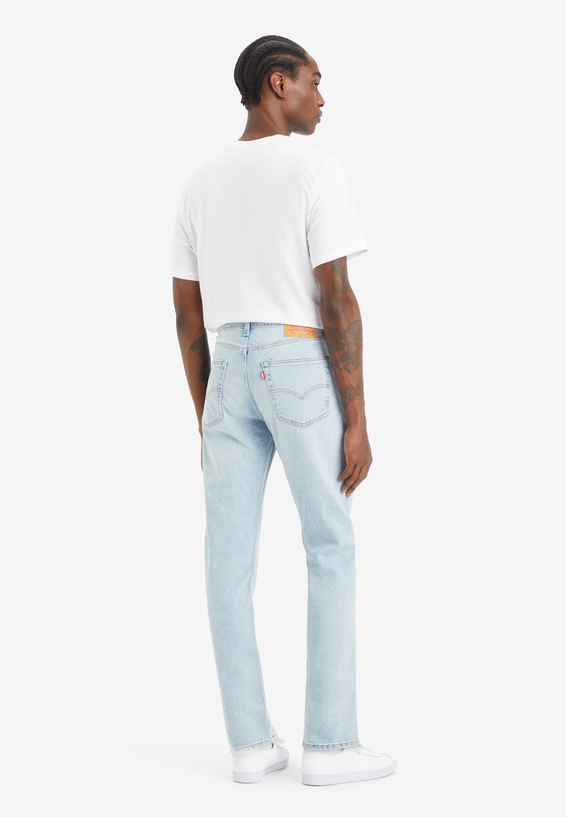 Lichtblauwe denim jeans met een rechte pijpdesign, voorzien van een leren logo patch op de achterkant en subtiele stikdetails. Gecombineerd met een wit shirt.