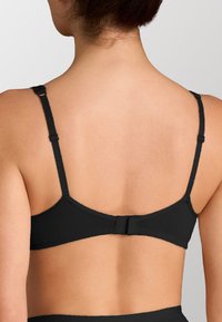 Sostenitore nero con spalline regolabili, chiusura a gancio e occhiello e tessuto liscio. Presenta un design semplice e senza cuciture, privo di decorazioni.