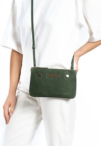 Groene leren schoudertas met een gestructureerde accent, rechthoekige vorm, ritsluiting en verstelbare schouderband. Voorzien van ronde hardwaredetails.