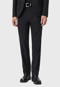 Pantaloni neri su misura con vestibilità dritta, realizzati in un tessuto liscio, con frontale piatto e abbinati a stivaletti neri in pelle.